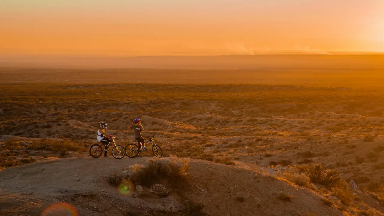 Due persone in bicicletta al tramonto su un’altura sopra la savana